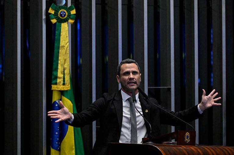 Cleitinho Azevedo habla en la tribuna del Senado de Brasil, con la bandera nacional detrás.